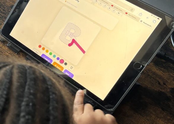 A child tracing a letter in a learning app on a tablet